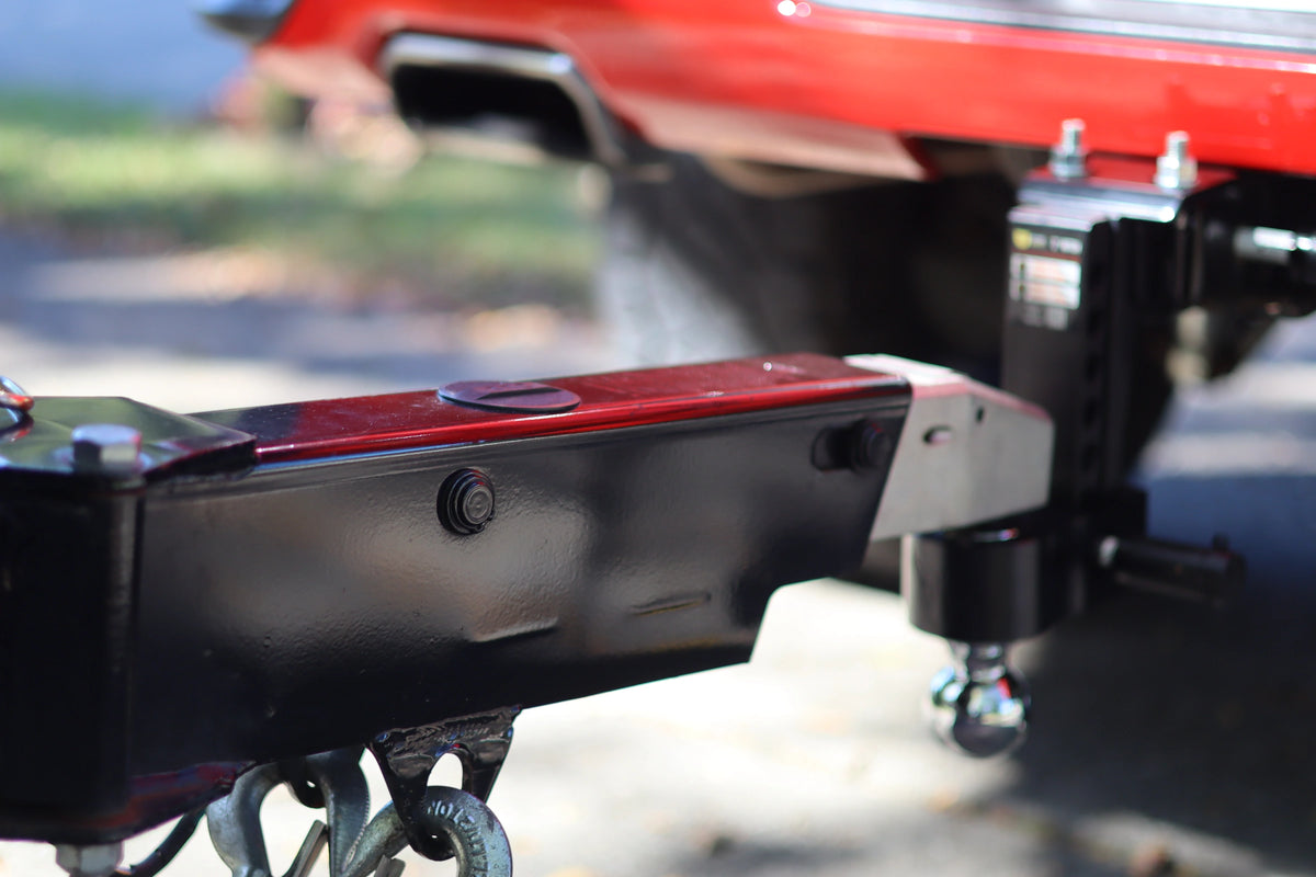 Close-up of a trailer coupler connected to a Black YakJak adjustable hitch on a red truck.